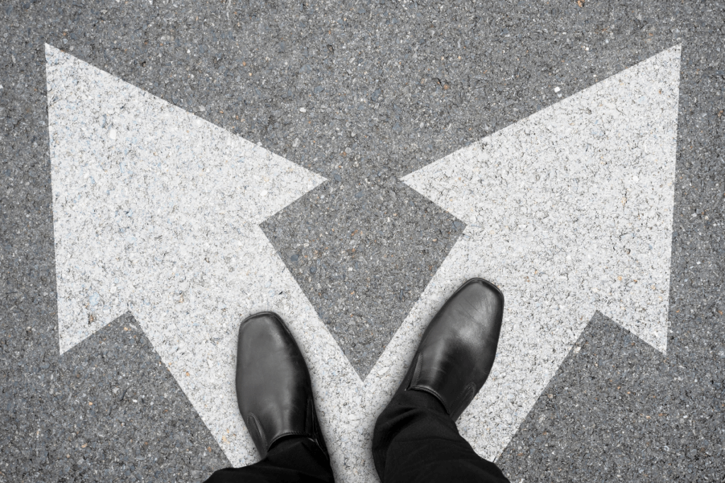 A person standing at a crossroads with two white directional arrows pointing in opposite directions, symbolizing a decision-making moment